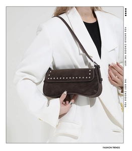 Detail of dark brown suede baguette bag with silver rivets and vintage shoulder strap