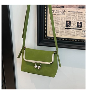 Detail of green leather crossbody bag featuring silver ball-clasp frame closure