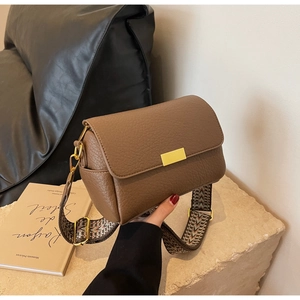 Gros plan du sac bandoulière marron grainé avec sa large sangle géométrique