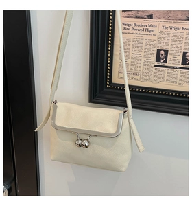 Detail showing cream leather texture and vintage metal ball clasp on small square bag