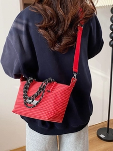 Fashionable red plaid crossbody bag with contrast woven handles shown on a model