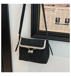 Close-up of black suede crossbody bag with vintage silver ball kiss-lock and slim strap