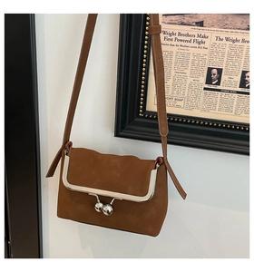 Detail of vintage brown suede crossbody bag featuring a silver metal clasp closure
