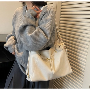 Detail of cream large tote bag with teddy bear charm and striped scarf decoration