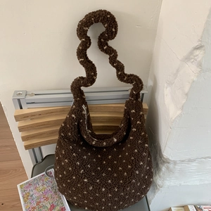 Dettaglio borsa a tracolla marrone scuro con pois bianchi e manico a forma di onda