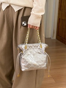 Silver quilted bucket bag with chain strap and drawstring detail shown by a model