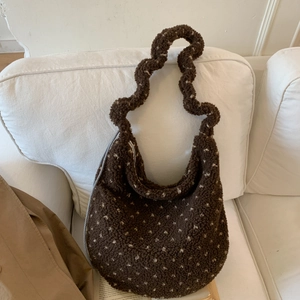 Dettaglio borsa hobo marrone in peluche con pois bianchi su un divano bianco
