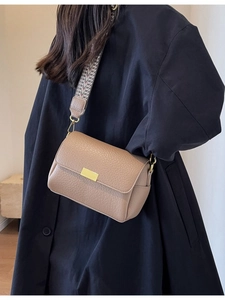 Sac bandoulière kaki avec large bandoulière et détails dorés sur un mannequin