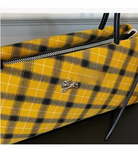 Detail of yellow tartan Boston bag featuring silver horse logo and premium metal zipper