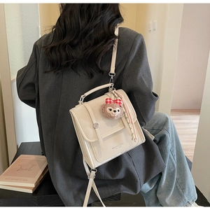 Detail view of cream vintage backpack with bear charm and striped scarf accessory