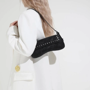 Detail of black faux leather bag with silver rivets and asymmetric saddle bottom design