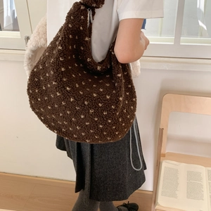 Dettaglio di una borsa a spalla in peluche marrone con stelle in una stanza luminosa