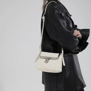 Weiße Crossbody-Tasche im Vintage-Stil mit Klippverschluss getragen an Lederjacke