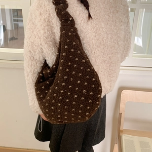 Borsa hobo marrone morbida con cuori bianchi indossata da una modella in interni caldi