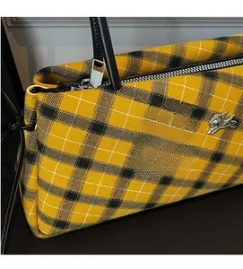 Detail showing yellow plaid fabric, black leather handle and silver metal running horse logo