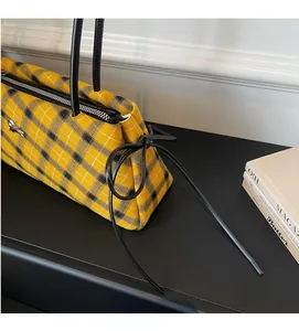 Detail of yellow plaid Boston bag with metal bee ornament and black ribbon bow accent