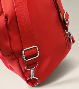 Detail of adjustable nylon strap with silver metal buckle and hook on red backpack