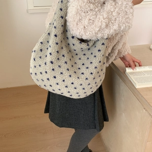 Dettagli dei motivi floreali sul tessuto in pile crema della borsa hobo a spalla