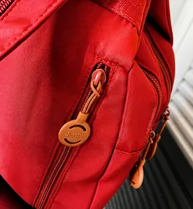 Detail of a smooth red nylon backpack zipper with a round branded rubber puller