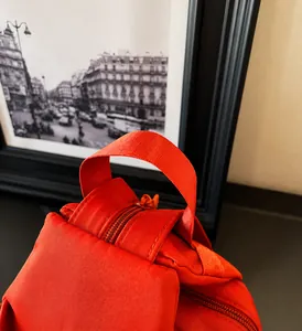 Close-up of reinforced strap handle and smooth zipper on orange oxford backpack