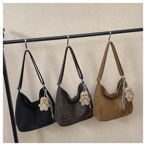 Detail of large hobo tote bags in black, dark brown, and khaki with teddy bear charms