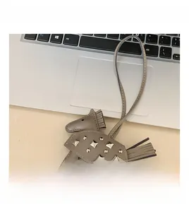 Detalle de un colgante para bolso de cuero gris en forma de caballo con tachuelas