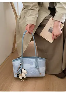 Détail du sac cabas bleu clair avec texture en tissu et accessoire breloque cheval