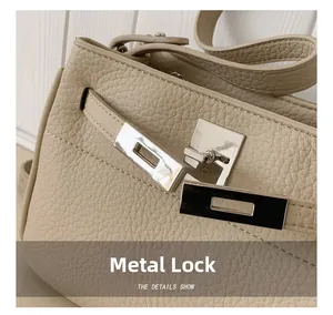 Vista macro de bolso de piel granulada beige con elegante cierre de giro en metal plateado