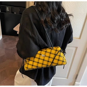 Detail of yellow and black plaid baguette bag with silver lion emblem on the front