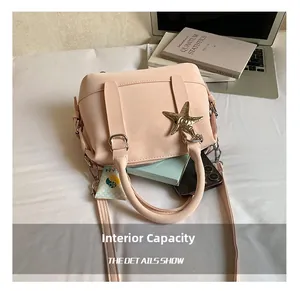 Internal capacity of light pink handbag showing makeup, phone, and starfish charm detail