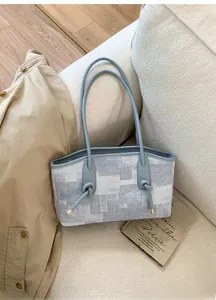 Détail du sac cabas en tissu texturé gris-blanc avec bordure en cuir bleu clair et nœud