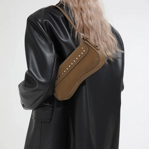 Detail of brown matte saddle bag featuring silver metal rivets and thin shoulder strap