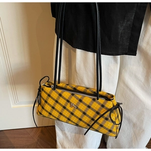 Close-up of yellow plaid canvas shoulder bag with silver horse emblem and leather straps