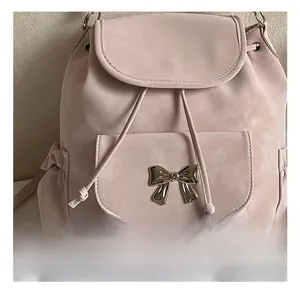 Close-up of pink suede backpack featuring a gold bow buckle and drawstring closure