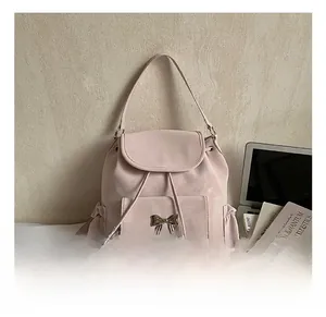 Detail view of pink suede backpack featuring a gold bow clasp and drawstring closure