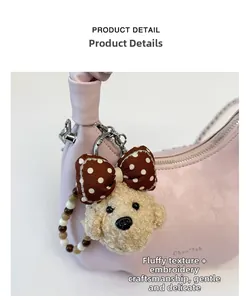 Close-up of light pink pleated dumpling bag with cute plush puppy charm and embossed logo
