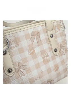 Détail du sac fourre-tout crème avec motif d'ours mignon et texture en cuir
