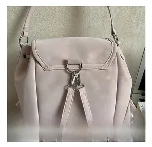 Detail view of pink suede travel backpack with metal hooks and drawstring side pockets