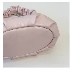 Detailed view of pale pink pleated soft leather texture on a minimalist dumpling bag
