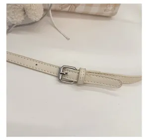 Détail de la bandoulière réglable en cuir crème avec boucle argentée et surpiqûres