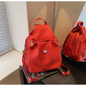 Detailansicht eines roten Nylon-Rucksacks mit Rundlogo und Reißverschluss-Details