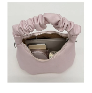 Detail view of pink pleated cloud bag interior showing capacity for cosmetics and phone
