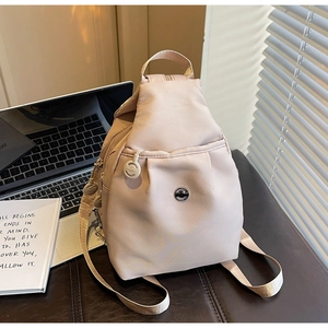 Nahaufnahme des apricotfarbenen Nylon-Rucksacks mit Reißverschlüssen auf dem Schreibtisch