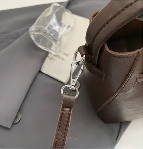 Detail of durable silver metal hook attachment on dark brown leather shoulder bag