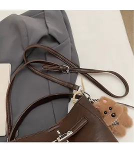 Detail of adjustable smooth shoulder strap and silver buckle on dark brown leather bag