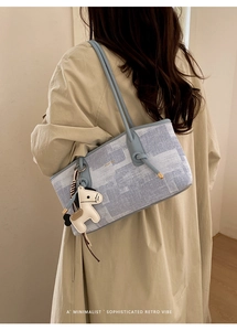 Détail du sac Boston bleu clair texturé avec charm cheval et bandoulière nouée