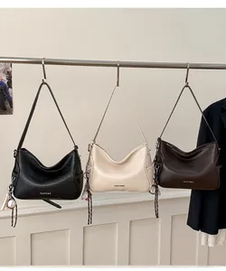 Detailed view of three minimalist tote bags in black, beige, and coffee textured leather