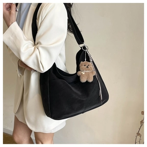 Vue latérale du grand sac hobo noir avec un charme d'ours et un ruban à rayures