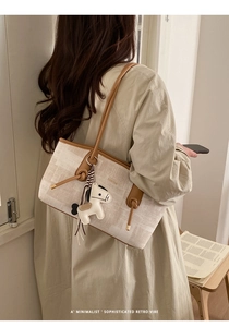 Détail du sac cabas en toile avec garniture en cuir et breloque cheval sur l'épaule