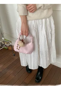 Detail of light pink pleated handbag featuring cloud handle and cute bear charm accessory